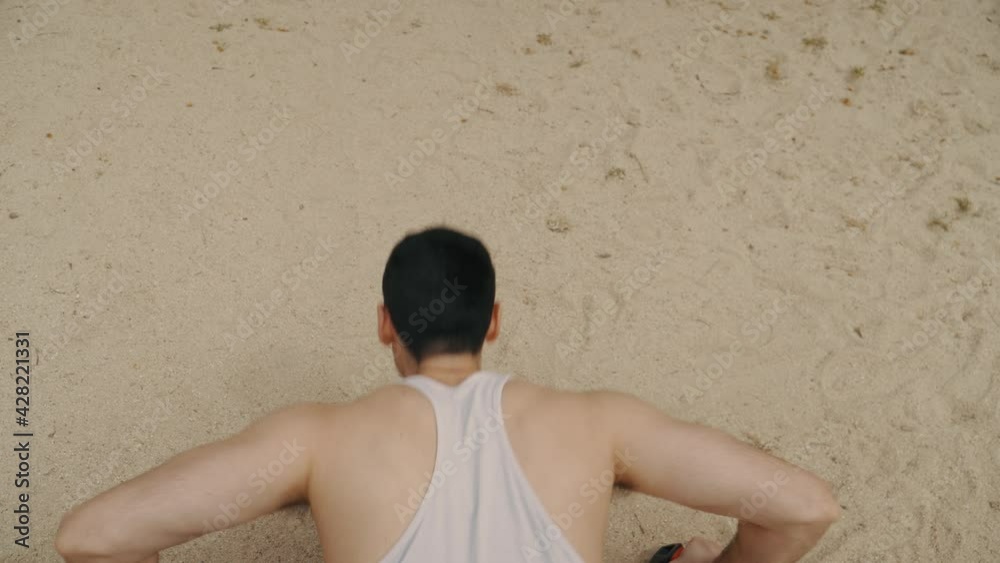 hombre haciendo flexiones sobre la arena, hombre musculoso con camiseta blanca haciendo ejercicio, vista aérea del hombre haciendo flexiones, vista superior de hombre haciendo flexiones