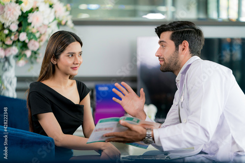 Male surgeon talking with female patient in clinic