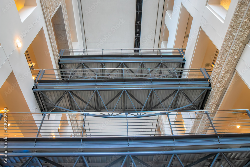 Obraz premium Three bridges in an office building spanning corridors over mezzanine with exposed structural steel deck elements, steel railings, nobody