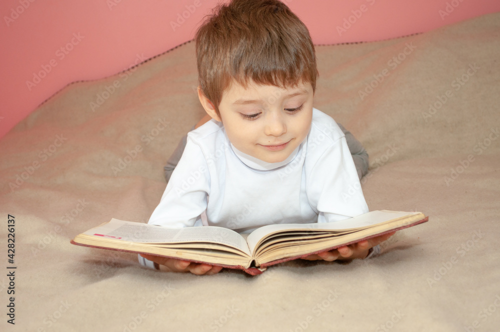 A preschool boy reads a book in the bedroom A preschool boy reads a book in the bedroom