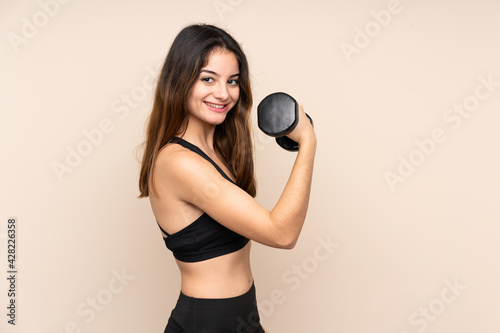 Young sport woman making weightlifting isolated on beige background