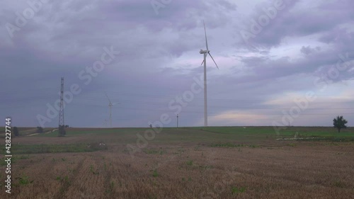 landscape with wind turbine working in the field during windy day
