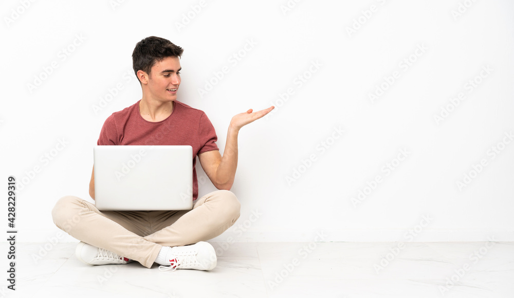 Teenager man sitting on the flor with his laptop holding copyspace with doubts Teenager man sitting on the flor with his laptop holding copyspace with doubts