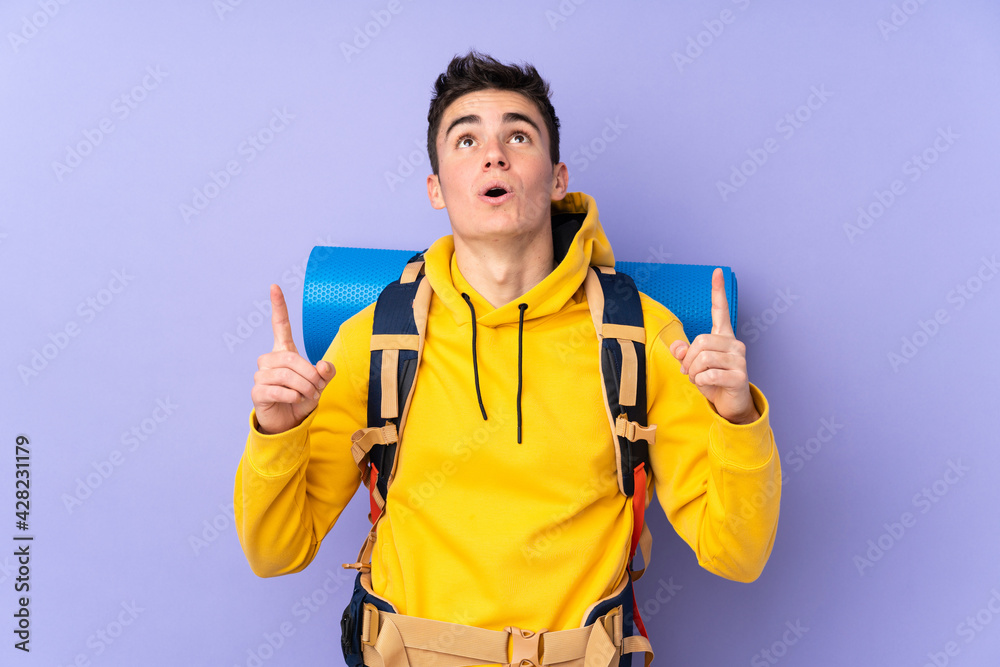 Teenager caucasian mountaineer man with a big backpack isolated on purple background pointing with the index finger a great idea Teenager caucasian mountaineer man with a big backpack isolated on purple background pointing with the index finger a great idea