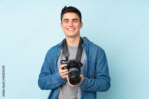 Teenager photographer man isolated on blue background