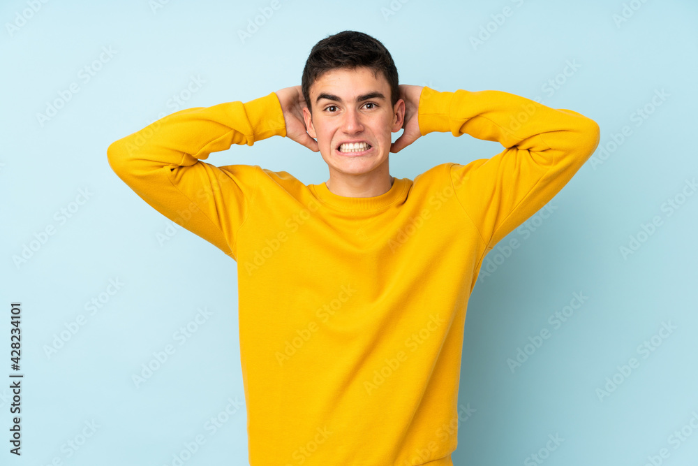Teenager caucasian handsome man isolated on purple background frustrated and takes hands on head