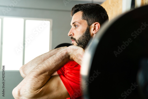 Young athlete lifting barbell with dumbbells exercising in gym