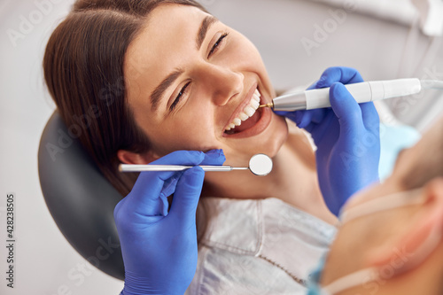 Female patient at dental procedure, doctor using dental instruments in modern dental clinic photo