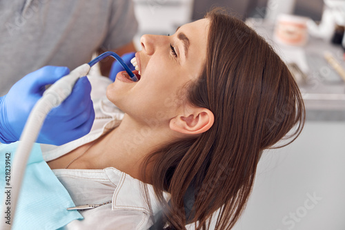 Female patient at dental procedure, doctor using dental instruments in modern dental clinic, close up.