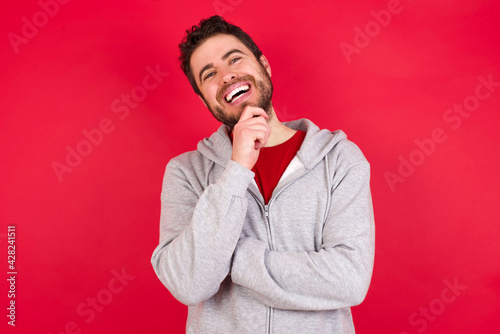 Young caucasian man wearing tracksuit over red background stares aside with wondered expression has speechless expression. Embarrassed model looks in surprise © Roquillo