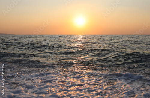 Sunset in yellow-orange tones on the summer sea in the evening