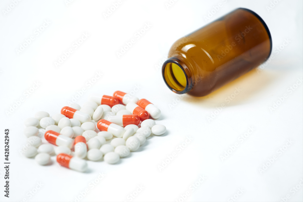 Set of multicolored pills poured out of a vial isolated on white background Set of multicolored pills poured out of a vial isolated on white background