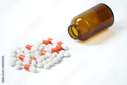 Set of multicolored pills poured out of a vial isolated on white background