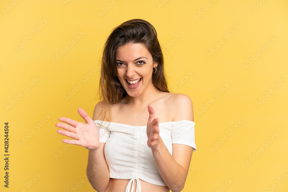 Young caucasian woman isolated on yellow background applauding after presentation in a conference