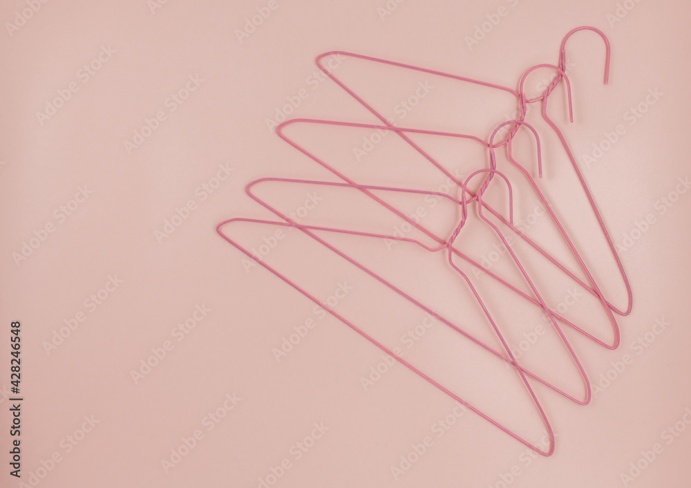 Metal pink hangers for clothes on pink background.  Empty cloth hanger template. Fashion blog,  sales,  store, online  shopping concept. 