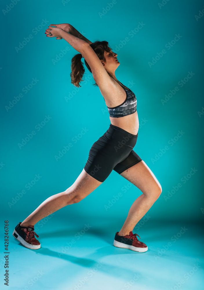 Attractive young sportswoman stretching arms before training
