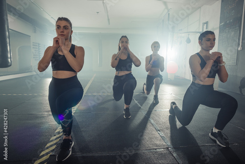 Group of sportswomen in sportswear doing lunge exercise at the gym with their left leg