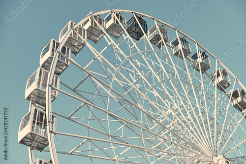 Ferris wheel on a background of turquoise sky. White ferris wheel on a sunny day.