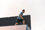 Sporty man training jumping over wall in skatepark
