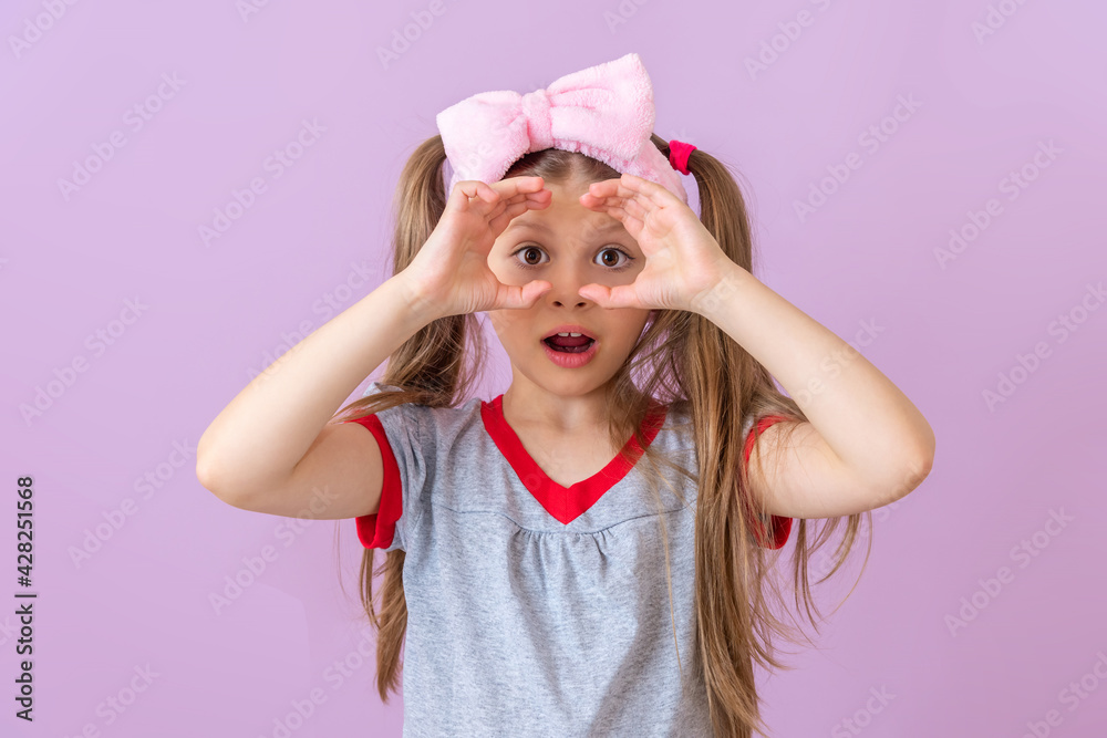 A little girl shows an imaginary pair of binoculars. A little girl shows an imaginary pair of binoculars.
