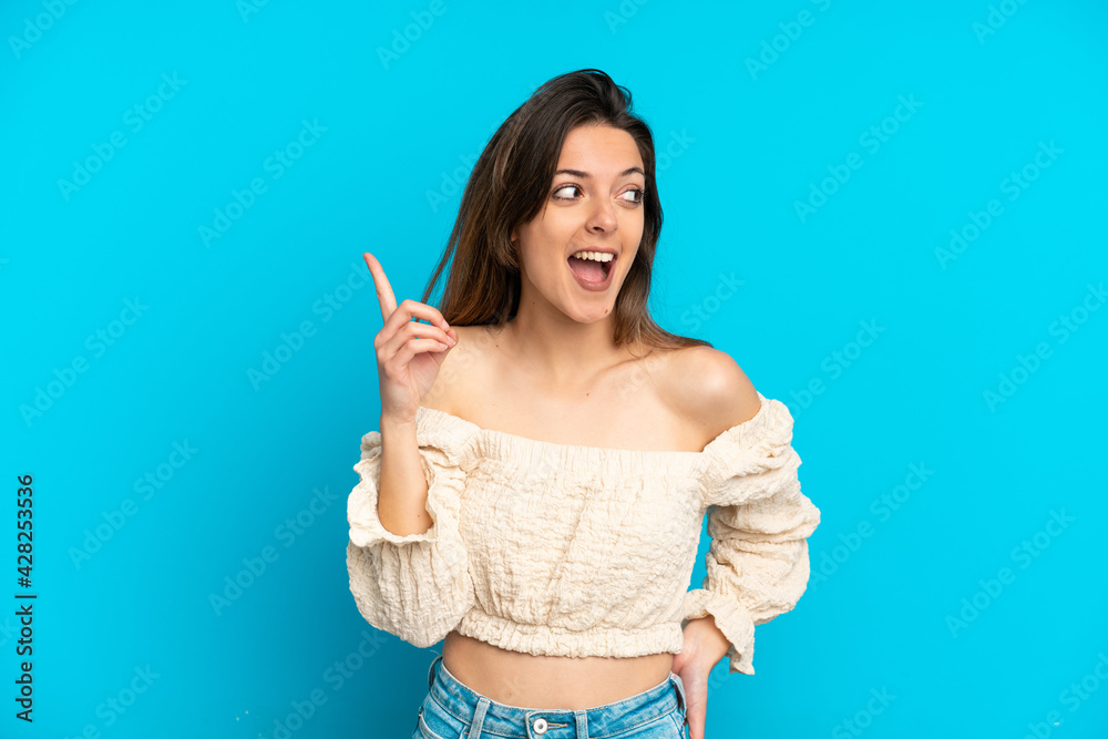 Young caucasian woman isolated on blue background intending to realizes the solution while lifting a finger up Young caucasian woman isolated on blue background intending to realizes the solution while lifting a finger up
