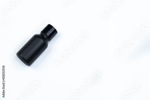 Glass bottle of hair care cream mixed with small black bamboo charcoal powder, placed on a white background.