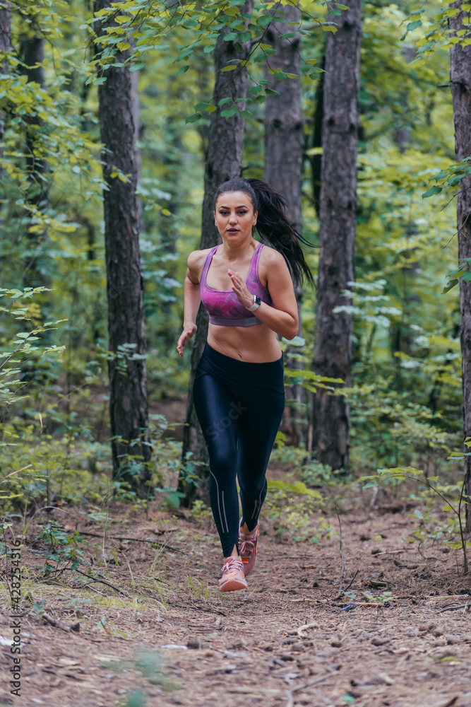 Young athletic sporty girl is jogging outside on a forest path Young athletic sporty girl is jogging outside on a forest path