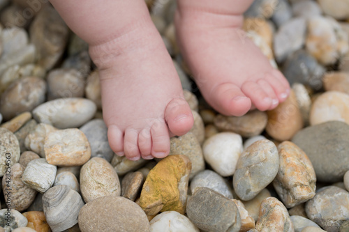 Two small bare feet of a little child standing on stones
