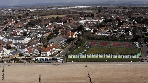 Felpham seafront in West Sussex with colourful beach huts on the coast and tennis courts in the background. Aerial Footage. photo