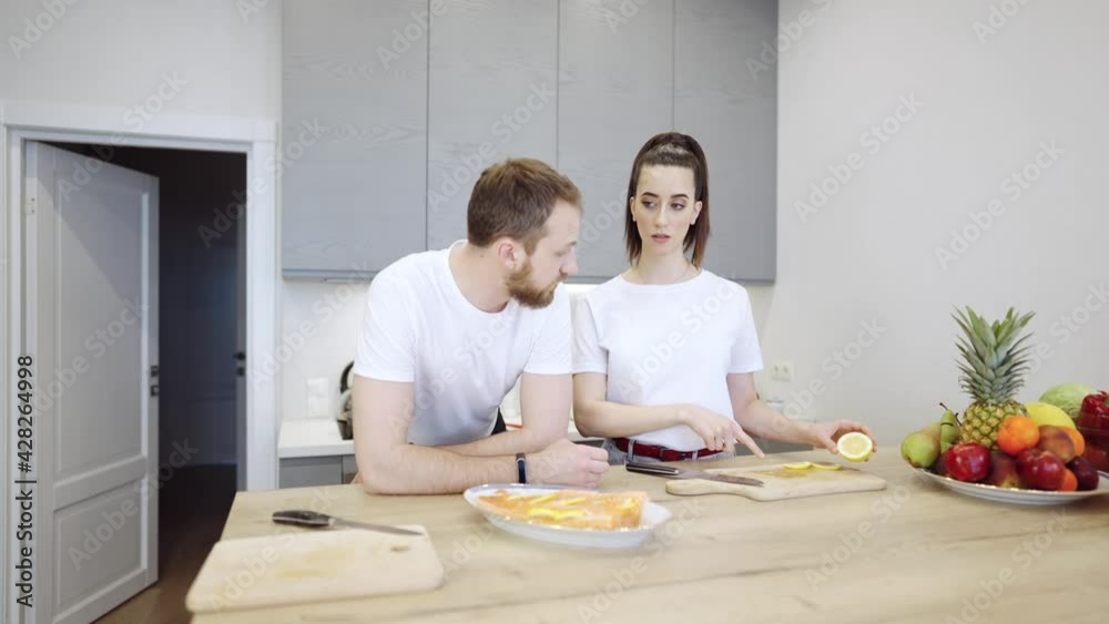 Young couple cooking salmon steak together at home in the kitchen. They are discussing healthy food and nutrition