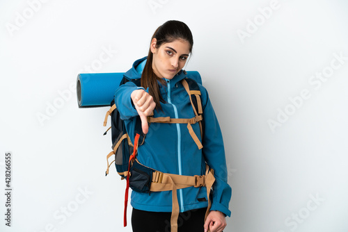 Young mountaineer man with a big backpack over isolated background showing thumb down with negative expression