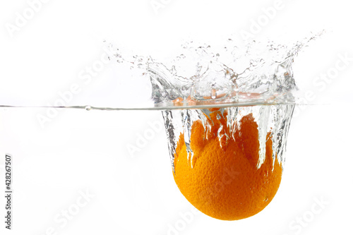 one ripe juicy orange falls into the water with splashes on a white background