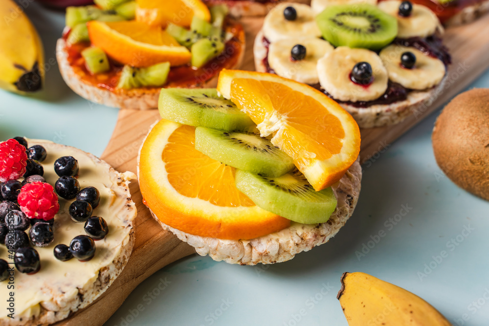 Crispy puffed rice cakes on table with fresh fruit kiwi banana apple blueberries and orange on the table - close up view on healthy organic vegetarian or vegan breakfast gluten free Crispy puffed rice cakes on table with fresh fruit kiwi banana apple blueberries and orange on the table - close up view on healthy organic vegetarian or vegan breakfast gluten free
