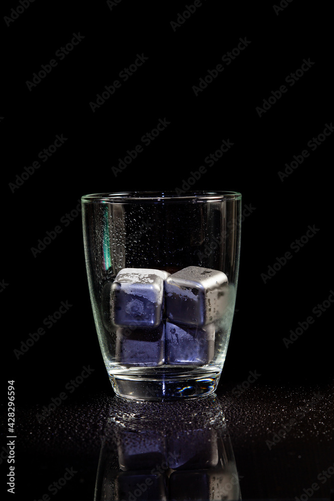 stainless steel cubes simulating ice in whisky glass on a black table. stainless steel cubes simulating ice in whisky glass on a black table.
