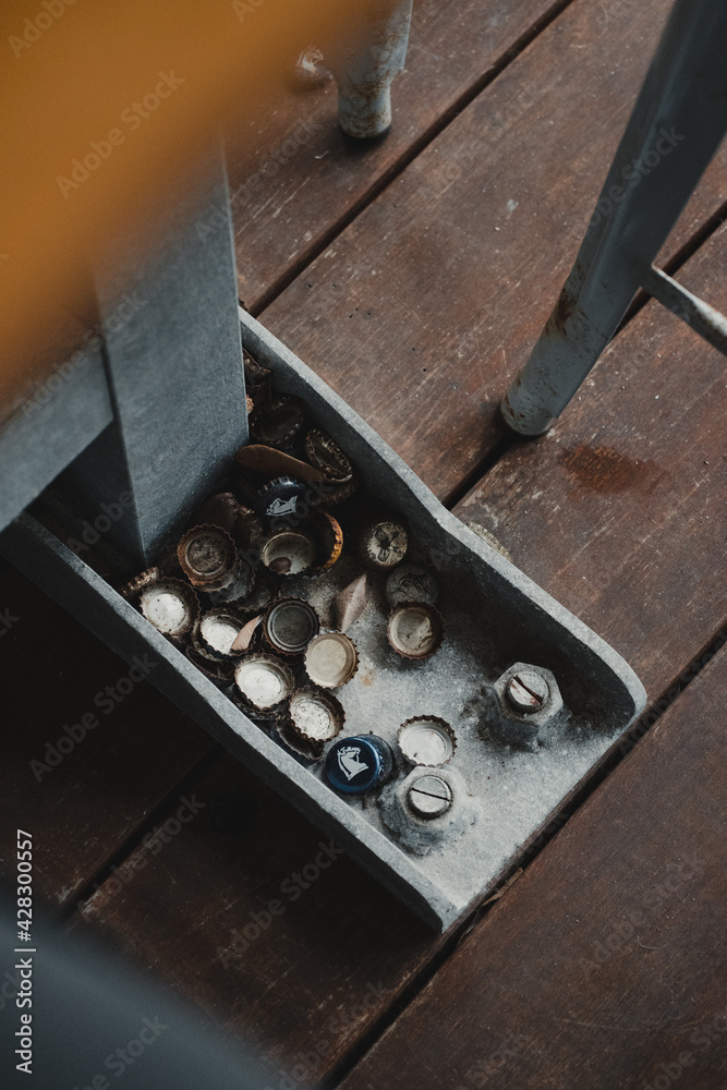 Collection of bottle tops under mini-bar with timber floor Collection of bottle tops under mini-bar with timber floor