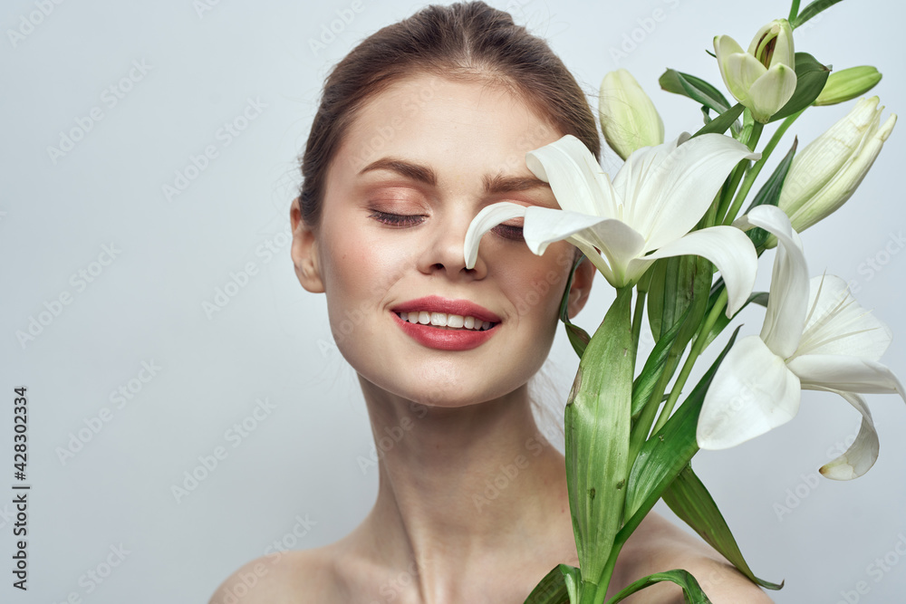Beautiful girl with a bouquet of white flowers on a light background naked shoulders clean skin spring Beautiful girl with a bouquet of white flowers on a light background naked shoulders clean skin spring