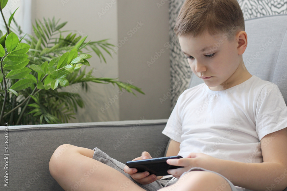 Fototapeta premium Child Engrossed in Smartphone at Home
