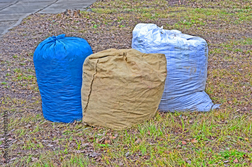 househo;d bags trash on the grass, refused packed dump on the street, polluted environment