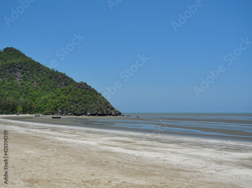 Sand and mud in water phenomenon, Fishing boat on the beach , Ocean waves splash the shore severely , Bay with mountain at Khao Sam Roi Yot national park , Thailand