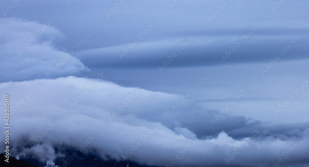 Panoramic View of Puffy Clouds over the Canadian Mountain Landscape. Colorful Winter Sunset Cloudscape Background. Taken between Squamish and Whistler, British Columbia, Canada.