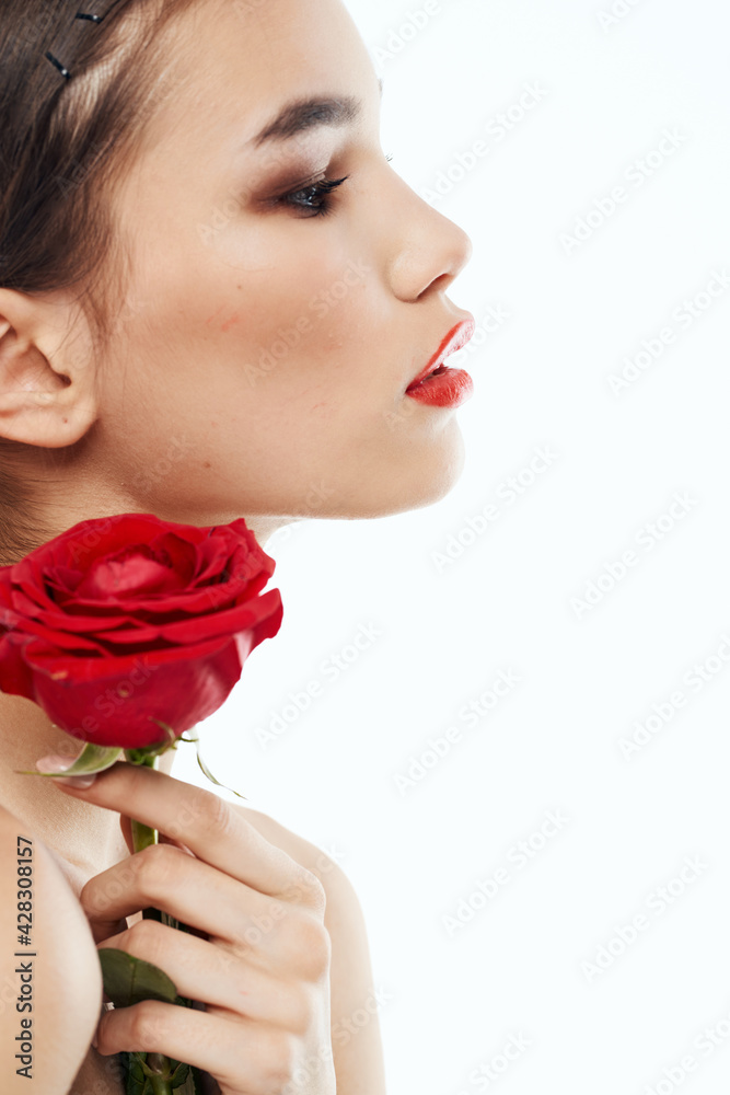 Side view of romantic woman with red flower near face Side view of romantic woman with red flower near face