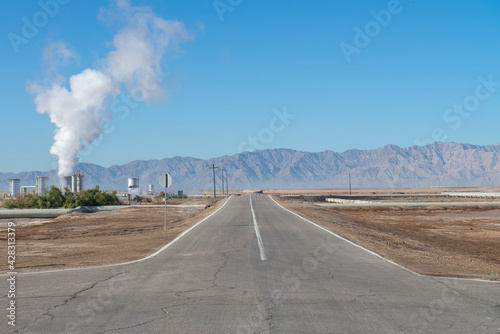 Geothermal power field with mountains in the background and the moon in the blue sky © Victor
