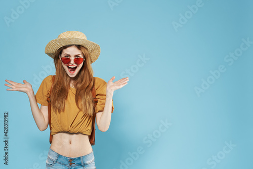 cheerful woman in a hat wearing sunglasses backpack blue background