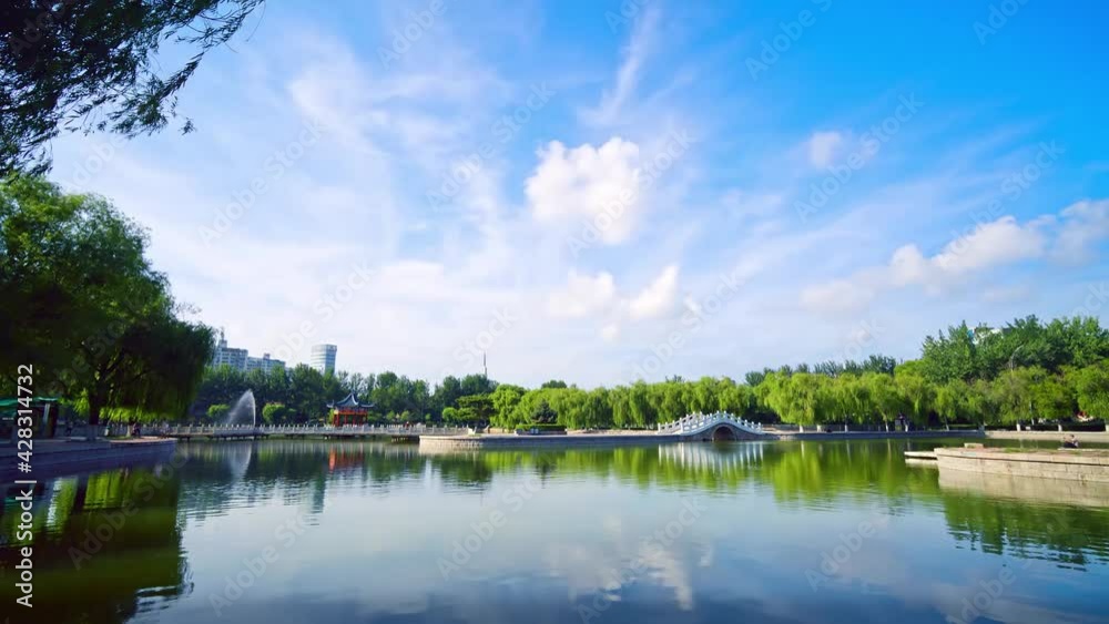 Time-lapse photography, a single-arch stone bridge across the lake with the weeping willows on the lakeside reflected in the water, a beautiful corner of the park Time-lapse photography, a single-arch stone bridge across the lake with the weeping willows on the lakeside reflected in the water, a beautiful corner of the park