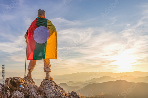 Male Hiker Standing On Top Mountain with Shan Ethnic National Flag in Myanmar photo