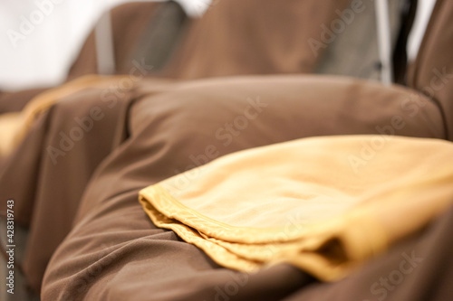 Yellow clean blanket on a reclining sofa chair with brown fabric cover in a room of a beuaty salon or parlor.