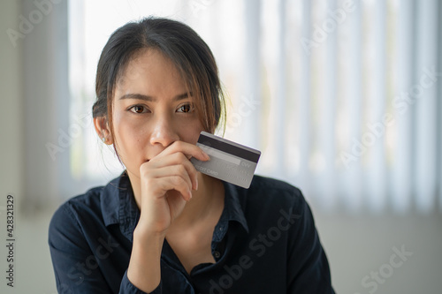 Portrait of asian woman holding credit card while looking at camera.