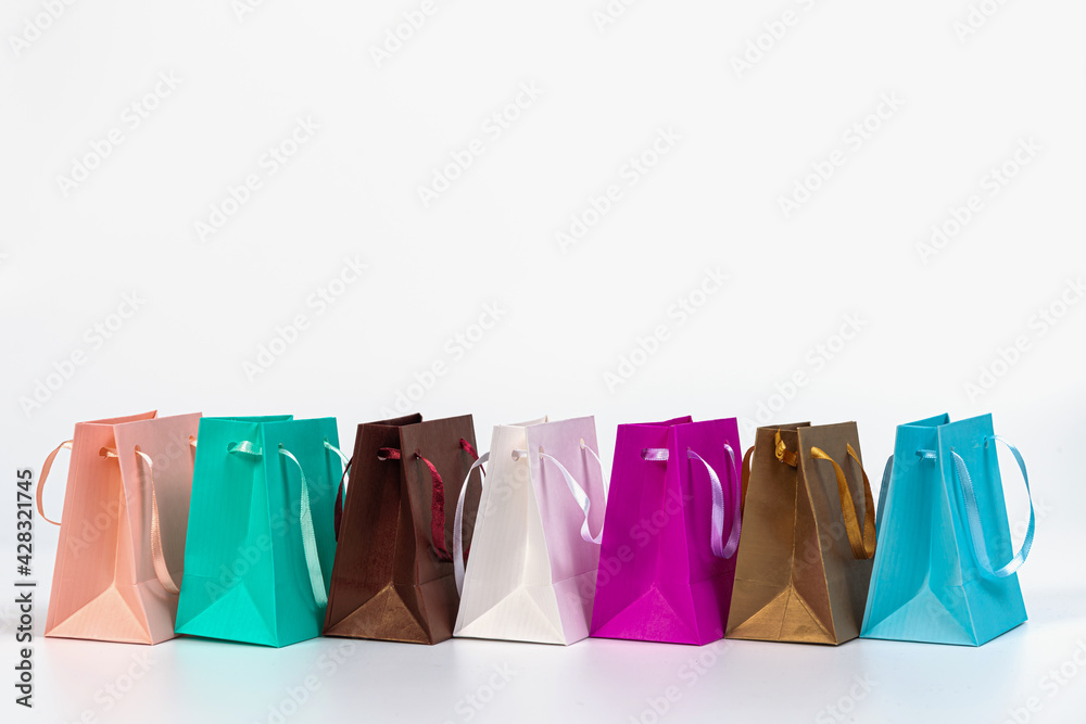row of colourful paper shopping bags isolated on white background, mockup for design