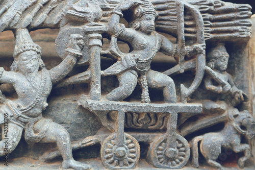 Carving on the stone of the Hoysala era. An ancient war is an archer in a chariot. photo