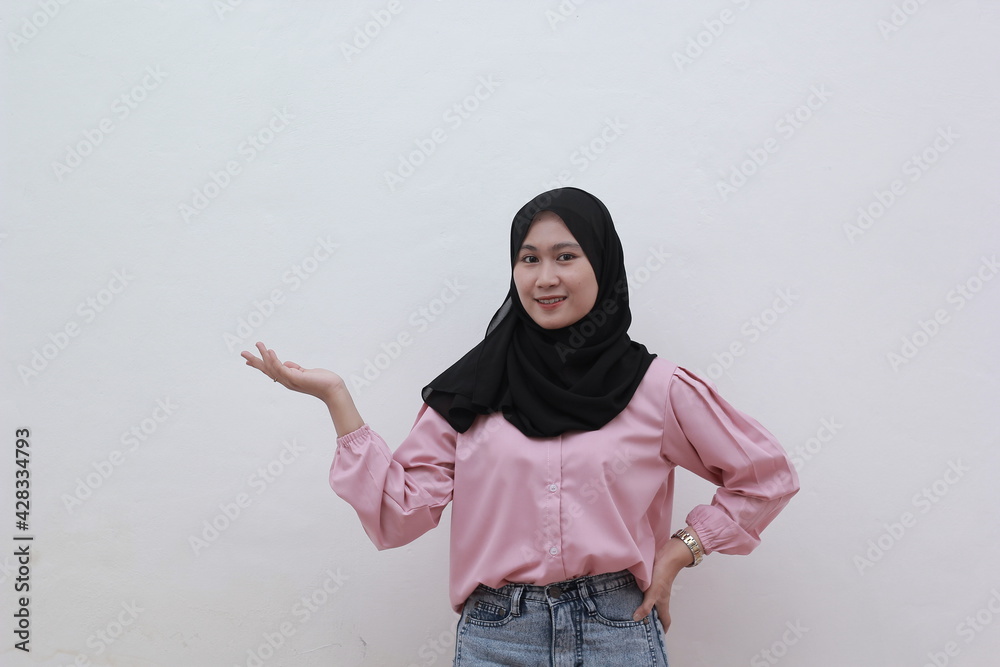 Portrait of cheerful young asian muslim woman pointing to copy space. Beautiful asian woman with casual dress. Beautiful muslim women. Portrait of cheerful young asian muslim woman pointing to copy space. Beautiful asian woman with casual dress. Beautiful muslim women.